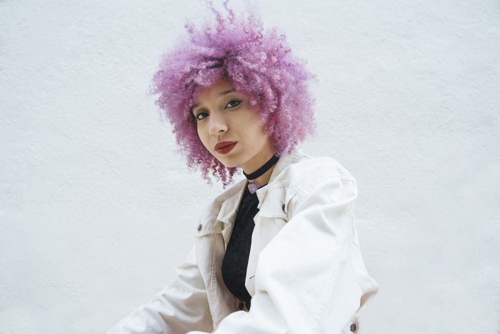 Stylish woman with pink hair looking at camera