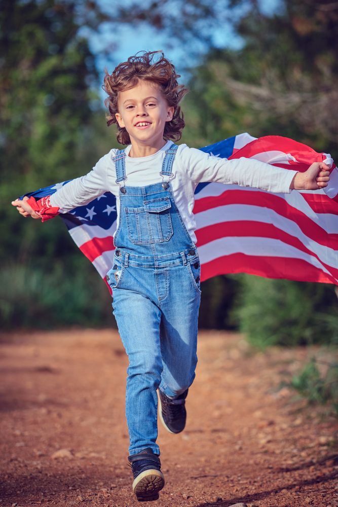 Little boy running with USA flag in nature