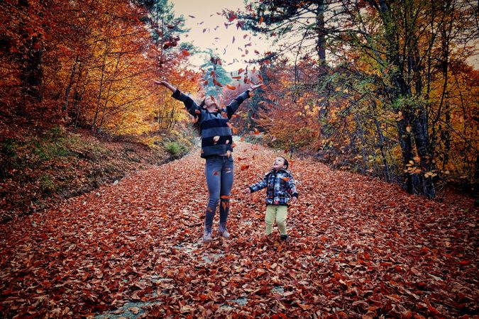 Mother and son playing with autumn tree leaves