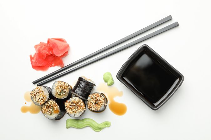 Delicious sushi rolls, soy and chopsticks on plain background, top view