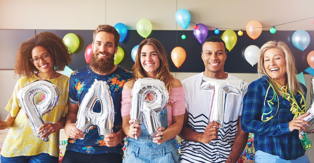 Friends standing with silver balloons reading “party”
