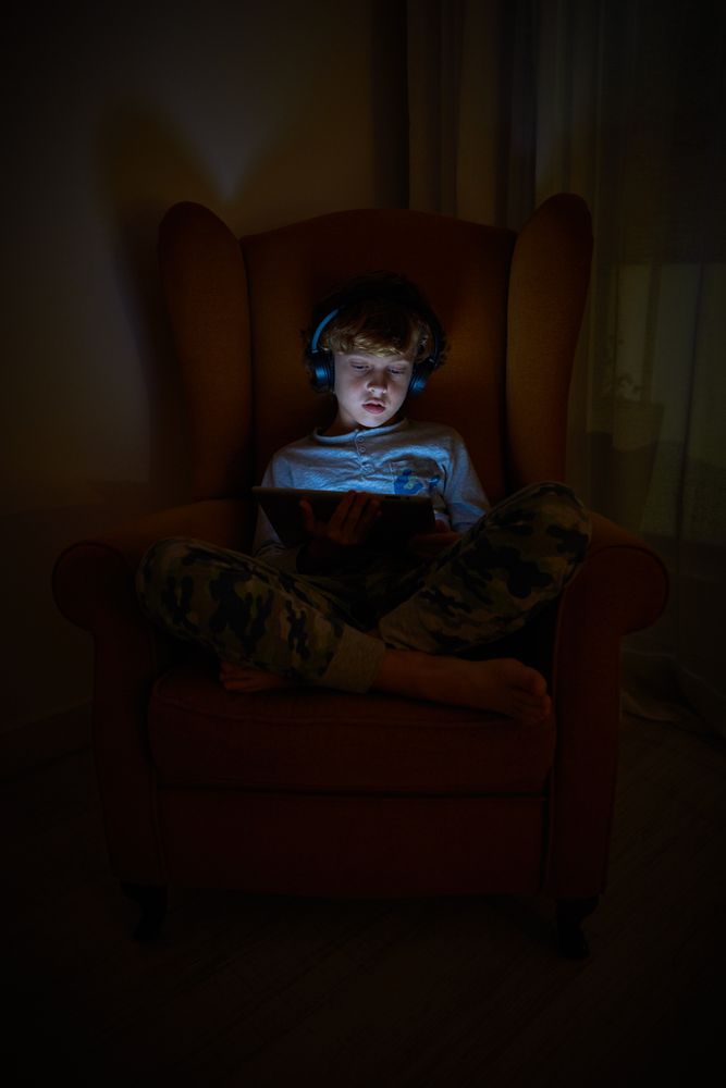 Curious boy playing on tablet in darkness