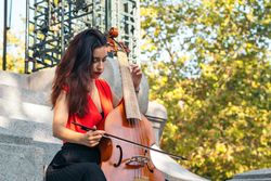 A young woman playing the cello outdoors