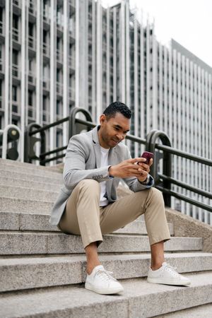 Man sitting on stairs using smartphone