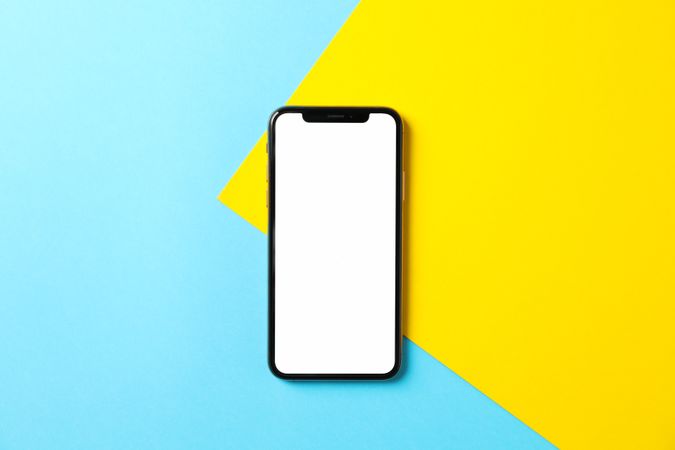 Phone with empty screen on two tone background, top view