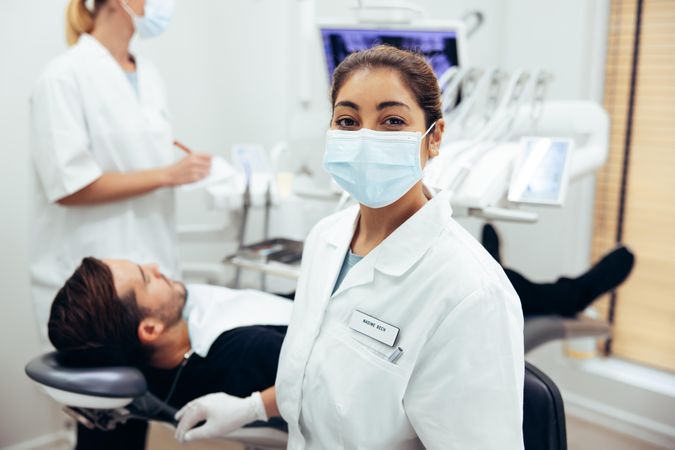 Dentist's assistant wearing face mask looking at camera