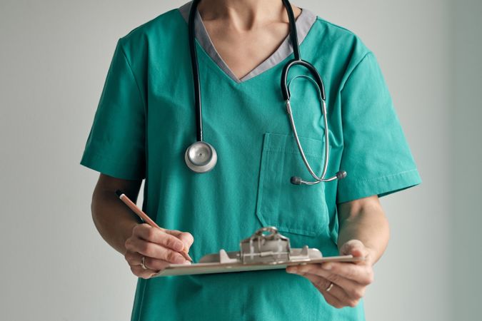 Faceless surgeon with clipboard and pencil at work