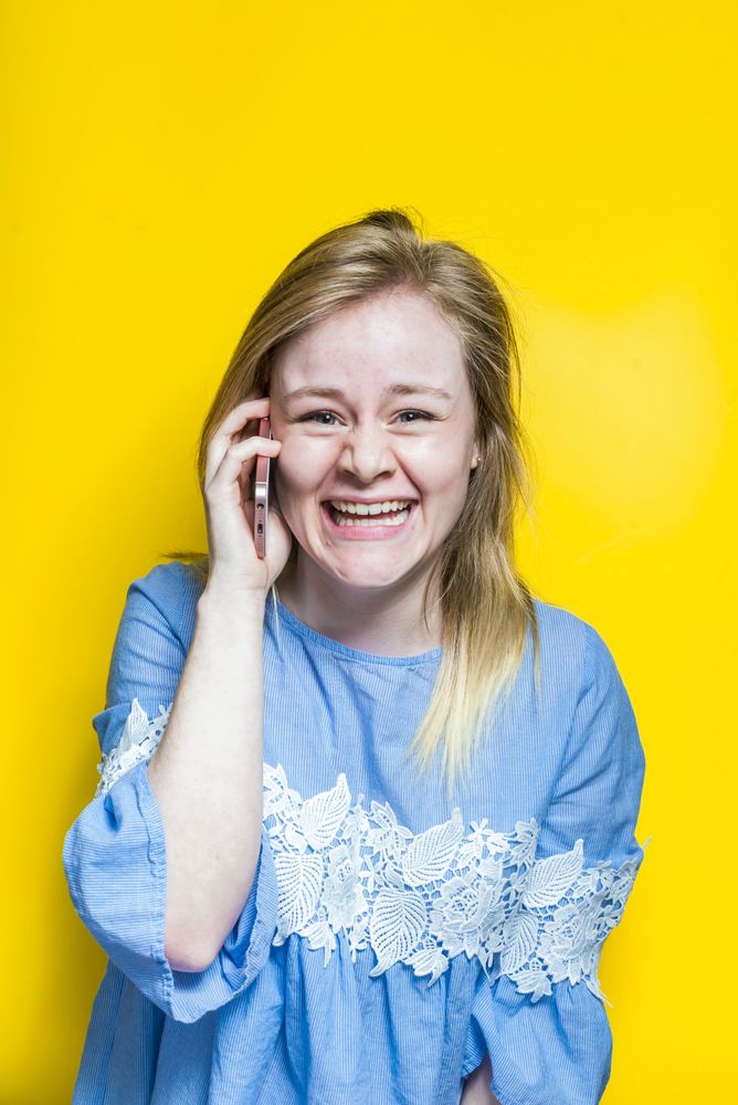 Excited young woman talking on smartphone