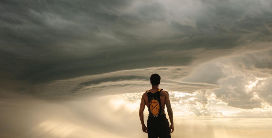 Man standing against cloudy sky and taking break after workout