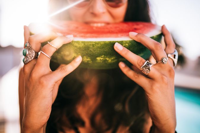 Woman wearing silver rings eating a watermelon slice