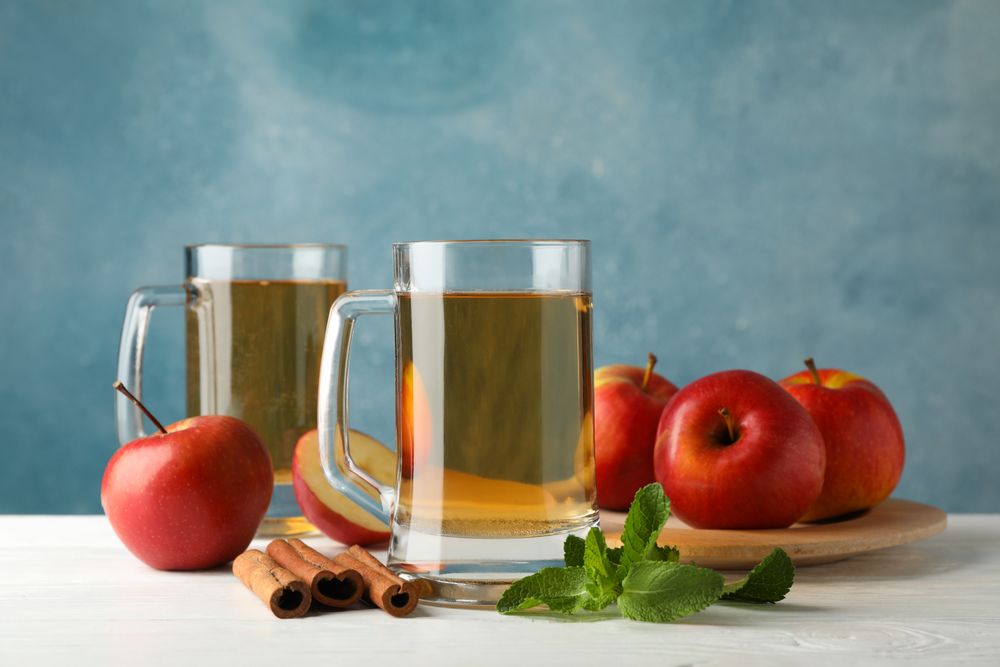 Composition with cider, cinnamon and apples on wooden background