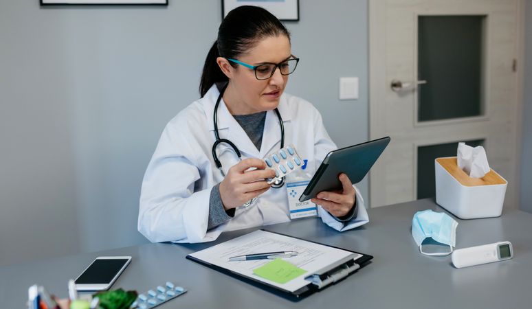 Female doctor reading drug leaflet on tablet