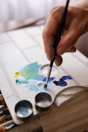 Close-up of a hand with a brush on a paint palette