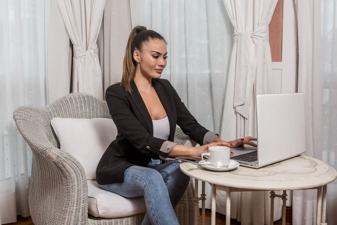 Woman in dark blazer using laptop computer in a hotel room