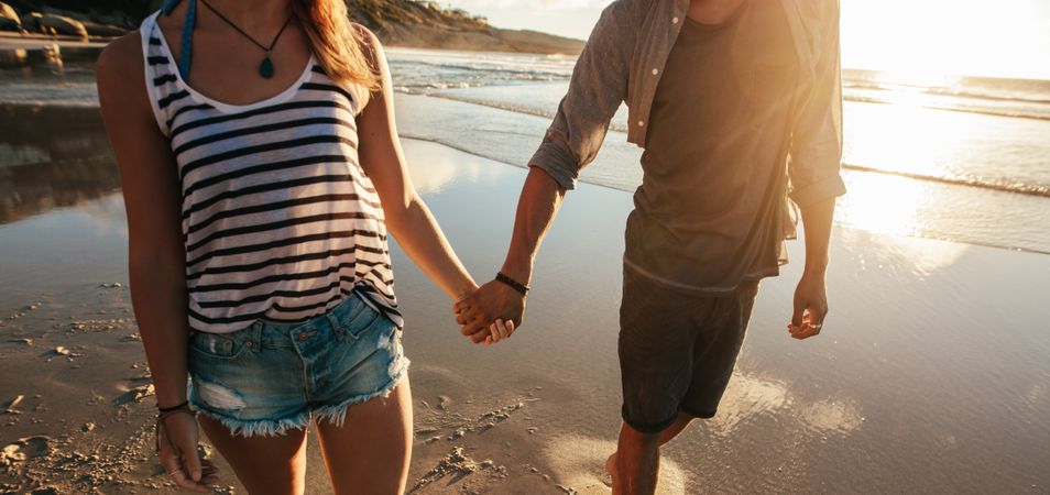 Couple holding hands at the beach during sunset