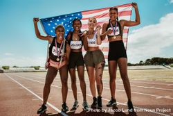 Happy multiracial athletes celebrating victory while standing together on racetrack 4OL3Lb