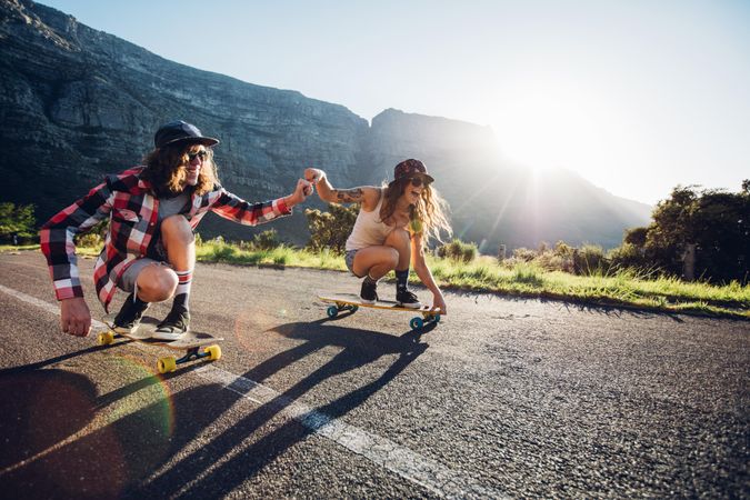 Happy young couple having fun with skateboard on the road