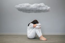 Woman with sad thoughts crying under a dark cloud