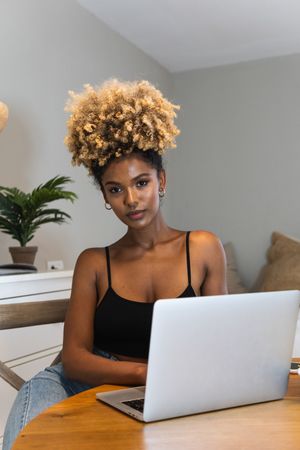 Black woman with laptop sitting on chair during breakfast