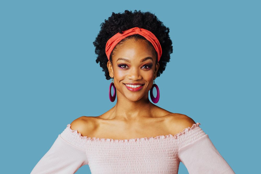 Studio shoot of smiling Black woman with hands on her hips