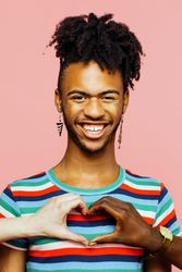 Portrait of a smiling man with earrings and heart shape with multiracial hands