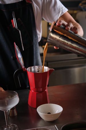 Unrecognizable bartender pouring cocktail into moka pot
