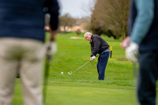 Man swinging on golf course towards friends