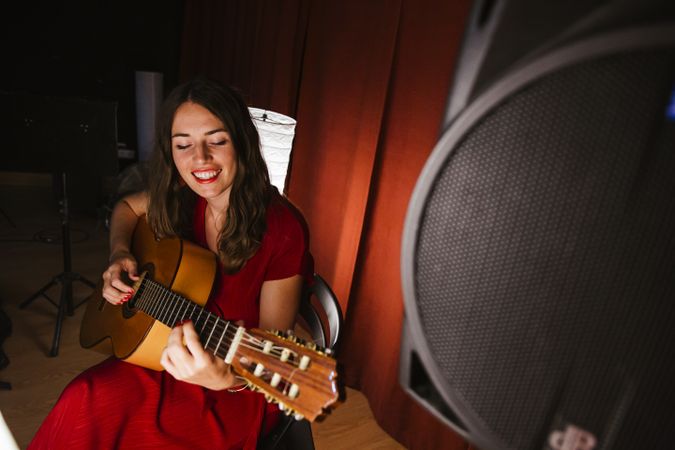 Creative woman singing and playing guitar on stage