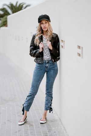 Stylish woman confidently leaning on white wall