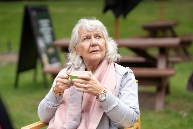 Woman sitting in park with cup of tea