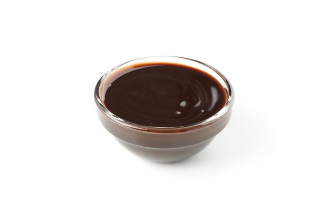 Bowl with melted chocolate isolated on light background
