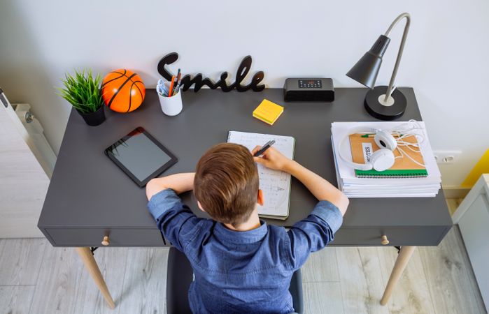 Top view of unrecognizable boy doing homework in his bedroom