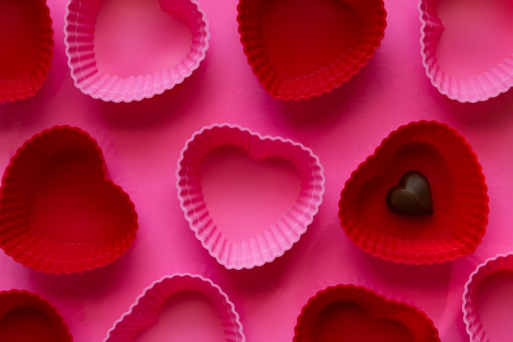Pink and Red Heart-Shaped Cupcake Molds with Heart Chocolate on a Pink Background.