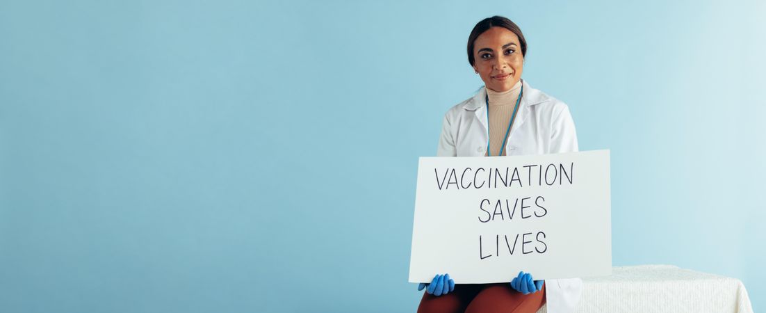 Healthcare worker holding banner of "Vaccination saves lives"