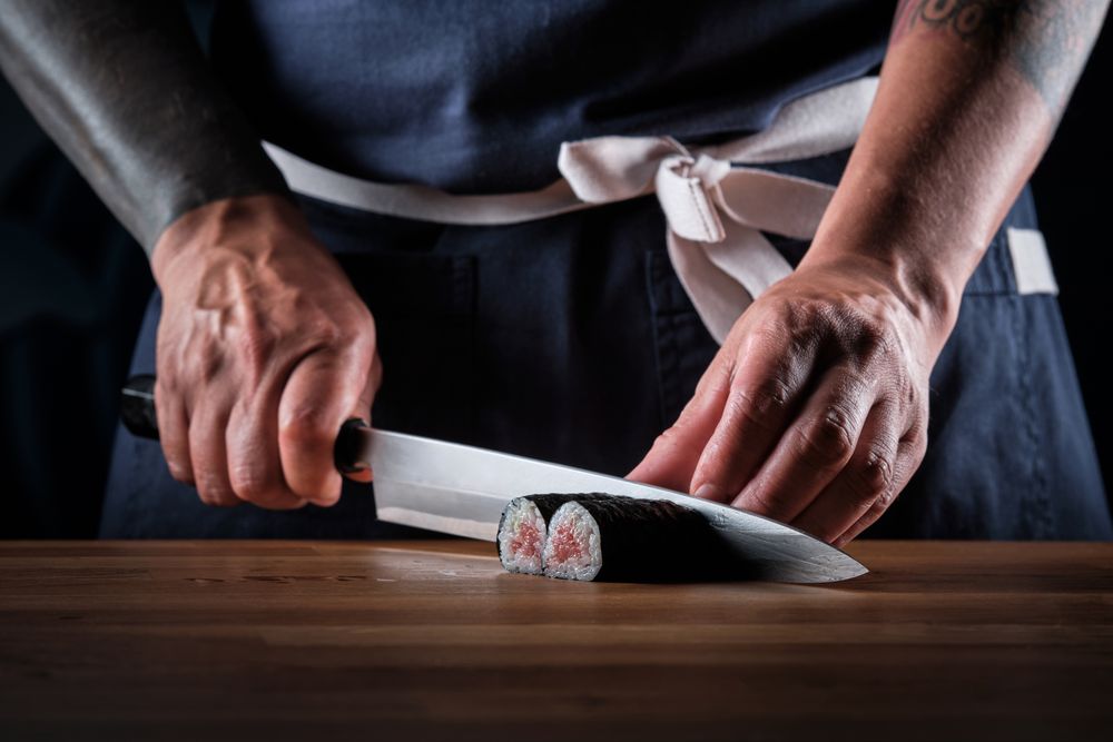 Male shushi man hands preparing different pieces of makis