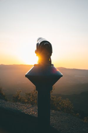 Astronomical telescope set on street at sunset