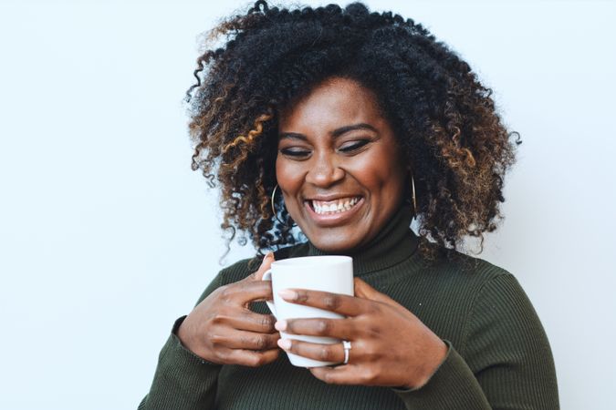 Joyful Black woman with cup of coffee