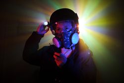 Thief in respirator with flashlight in darkness