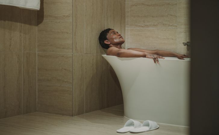 Woman lying in bathtub with her eyes closed