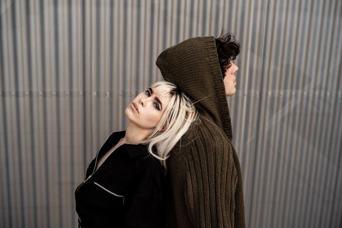 Loving man and woman supporting each other while standing back to back