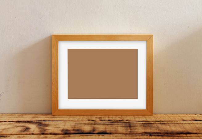 Rectangular picture frame with brown interior mockup on wooden desk