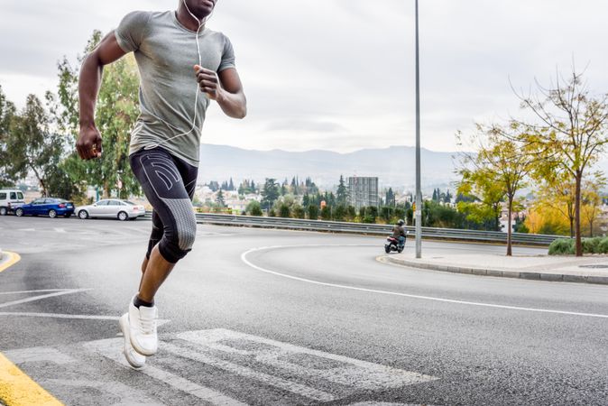 Body of male sprinting on city street