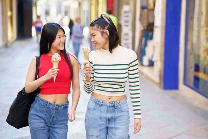 Two women walking down Spanish street with delicious ice cream cones