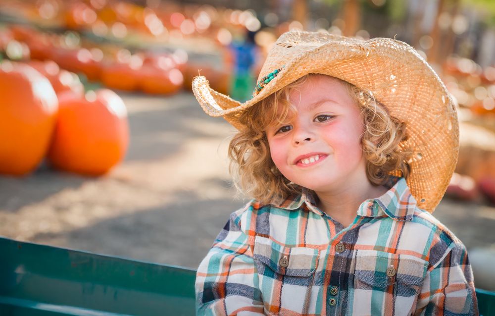 Cute Young Boy Wearing Cowboy Hat at Pumpkin Patch Farm.