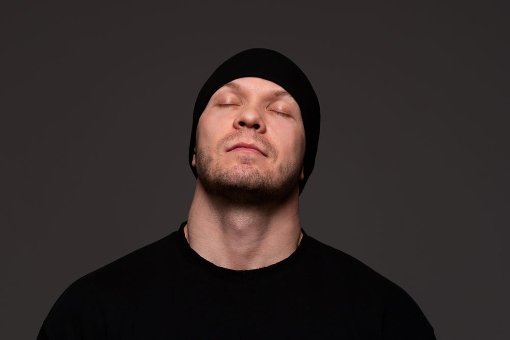 Man in beanie and sweatshirt with closed eyes