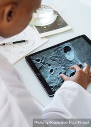 Close-up shot of young child using a tablet computer to see the moon's crater 0gRGjb