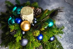 Christmas decorations in pine centerpiece with candle and peacock feathers