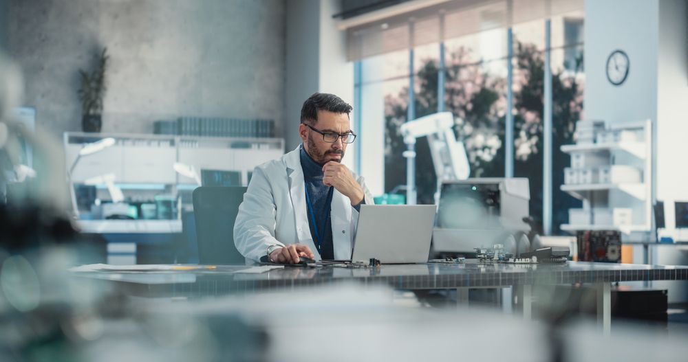 Portrait of a Professional Male Scientist Working in an Industrial Lab Using Laptop.