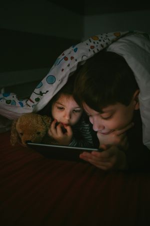 Siblings looking at the tablet in the dark