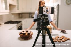 Young female blogger recording video on mobile phone camera in kitchen 5qqpK5